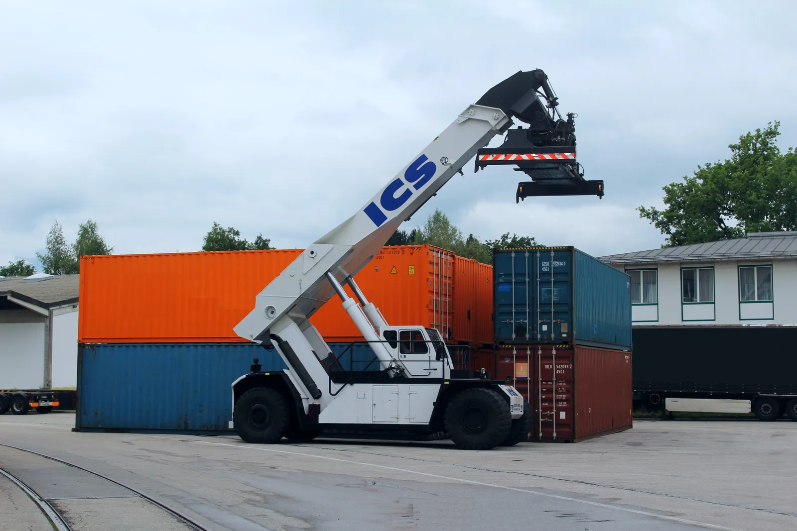 ICS reach stacker handling containers, with the terminal's rails in the foreground